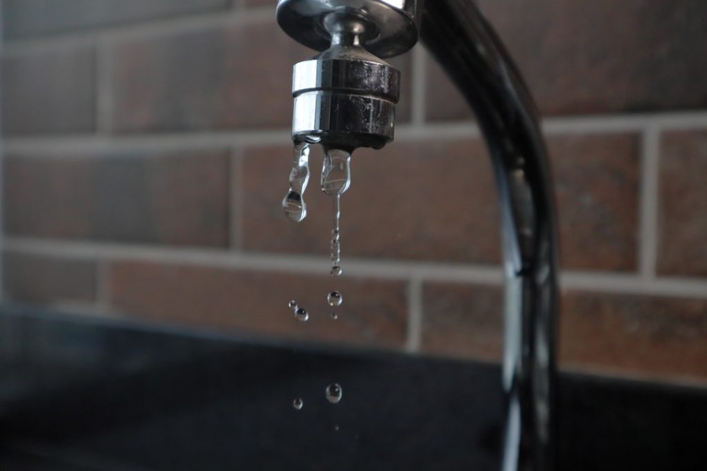 faucet drops water on brick background